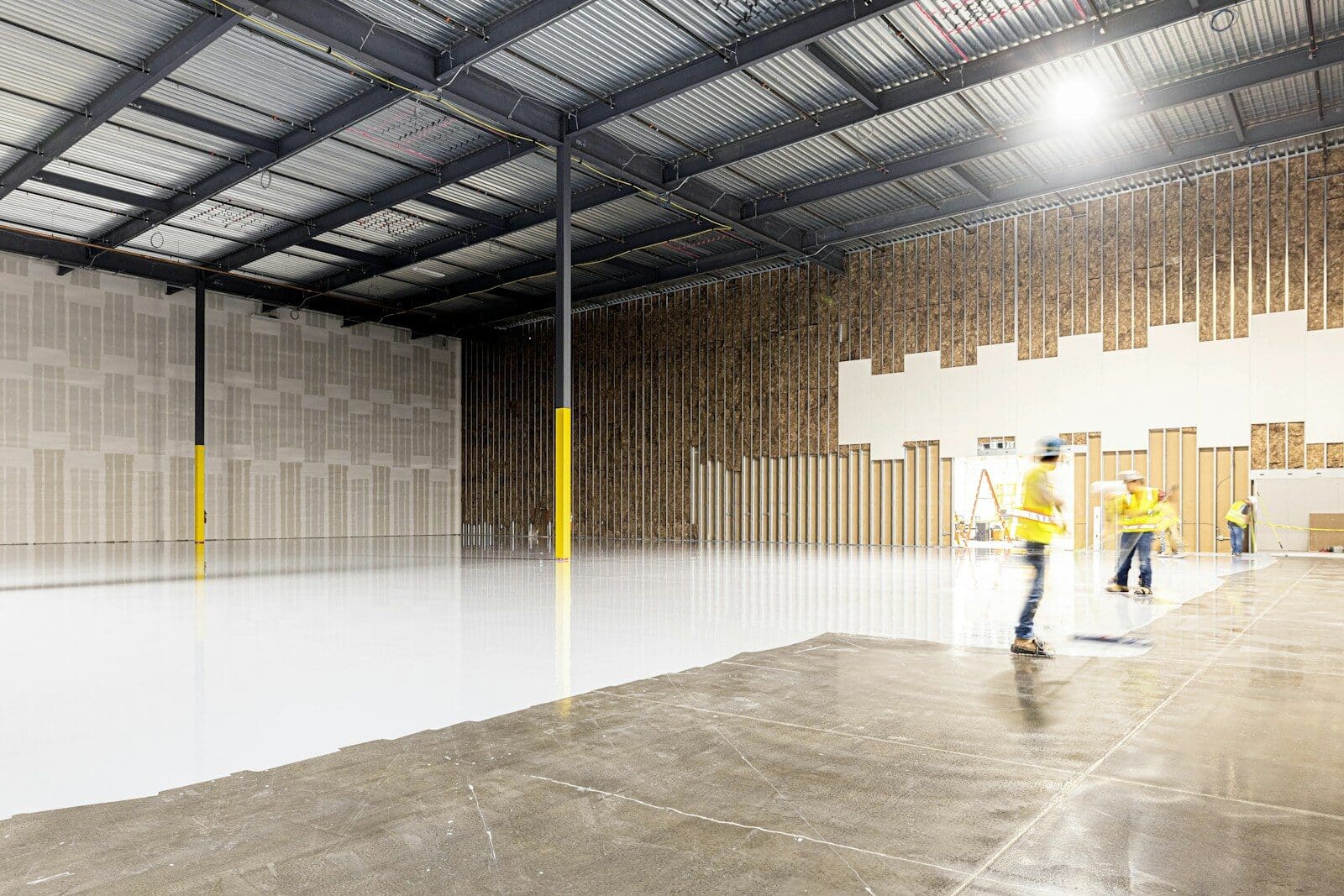 Two construction workers in a large empty warehouse